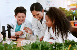 Teacher and two children examining plants and samples in a science lab