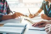 Shows the hands of two students who are working on a joint project at a table