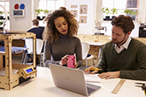 Man and woman in a design studio working on a laptop