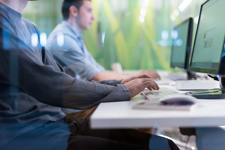 Students seating at a desk in front of computers