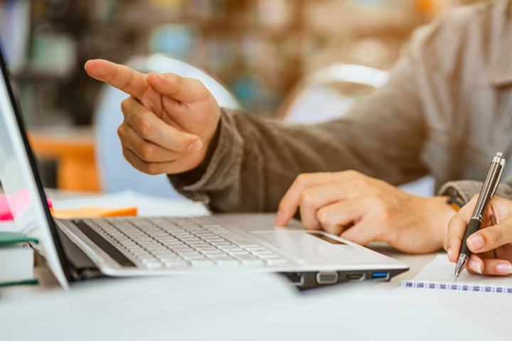 A student pointing at a laptop computer